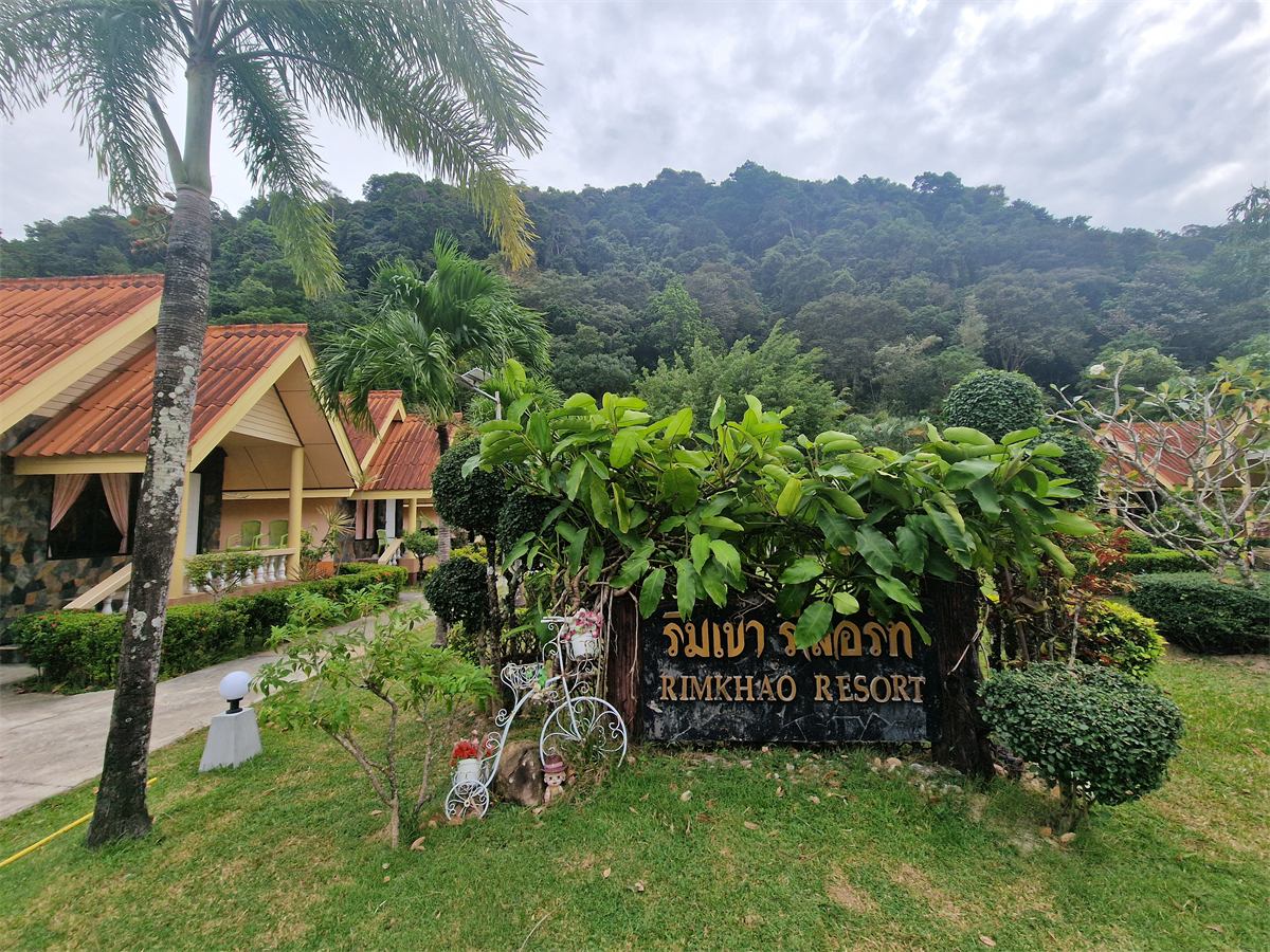 The Rim Khao Resort sign in the garden, with the jungle hill behind
